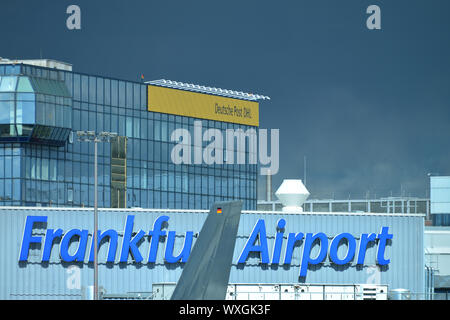 Frankfurt International Airport Logo with airplane crossing in front. Sky with thunderclouds. Frankfurt, Germany Stock Photo