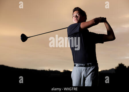 Golf player teeing off at sunset. Stock Photo