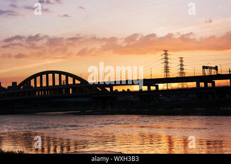 Sunset cityscape with silhouette of bridge over river in Taipei, Taiwan, Asia. The bridge was named MacArthur Bridge No. 1. Stock Photo