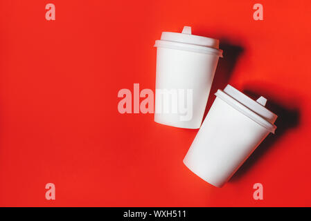 Two white paper cups on a red background. Stock Photo