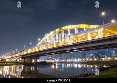 City night scene with illuminated bridge over river in Taipei, Taiwan, Asia. The bridge was named MacArthur Bridge No. 1. Stock Photo