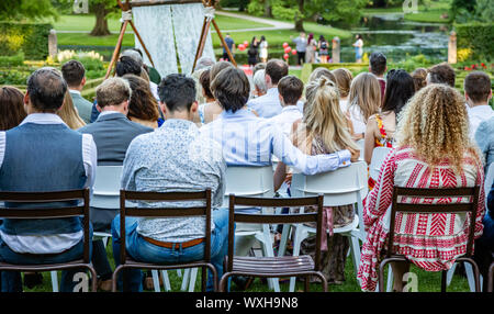 Rotterdam, Netherlands. June 29, 2019. Ijsvrij festival in a park. People are sitting, waiting for a ceremony to be start. Rear view, blur nature back Stock Photo