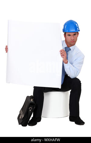 businessman with a helmet on his head holding a blank poster Stock Photo