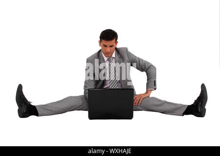 Businessman using his laptop with his legs spread apart Stock Photo