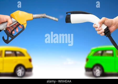 electric car and gasoline car concept. hand holding gas pump and power connector for refuel Stock Photo