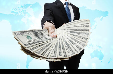 Business Man Displaying a Spread of Cash over blue world map background Stock Photo