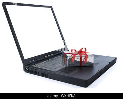 Small gift wrapped with a red ribbon over a black laptop isolated on white. White copy space on screen. Stock Photo