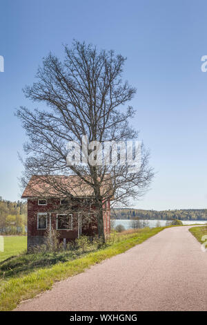 An old abandoned house and road in a rural countryside landscape. Aland Islands, Finland. Stock Photo