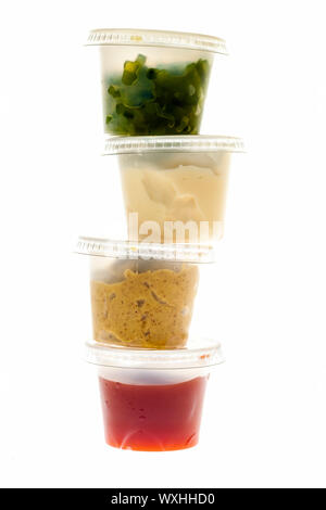 Relish mustard ketchup and mayonnaise condiments in clear containers stacked on white background Stock Photo