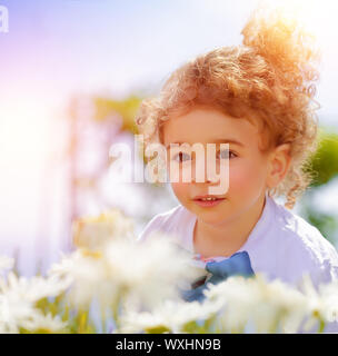 Closeup portrait of cute little boy on daisy field, having fun in beautiful park, summer holidays, recreation outdoors, carefree childhood Stock Photo