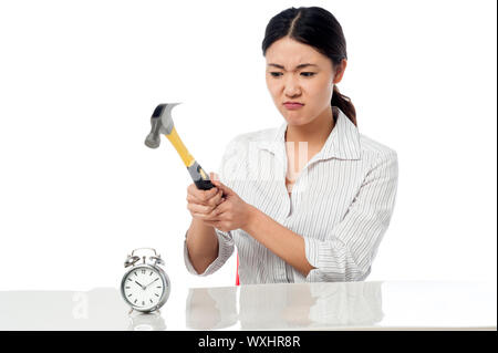 Angry business woman smashing an alarm clock with hammer. Stock Photo