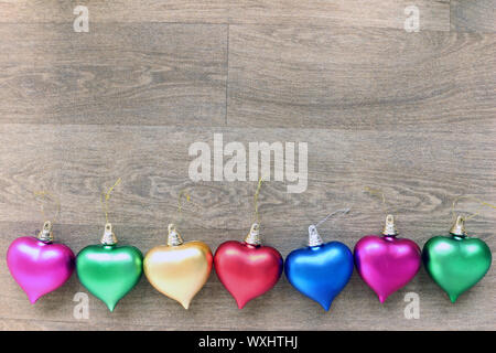 A row of colored hearts on a wooden background Stock Photo