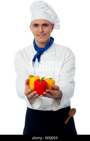 Male chef in uniform holding capsicums Stock Photo