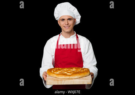 Isolated chef holding bread, black background. Stock Photo