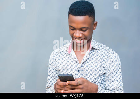 black african young hipster smiling using mobile phone, reading text, browsing internet, watching online videos Stock Photo