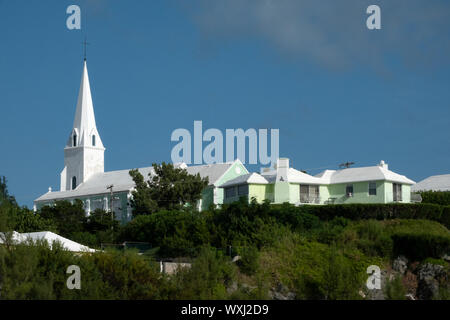 A white painted church in Bermuda against a blue sky with foreground greenery Stock Photo