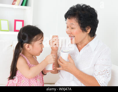 Eating yogurt. Happy Asian family eating yoghurt at home. Beautiful grandmother and grandchild, healthcare concept. Stock Photo