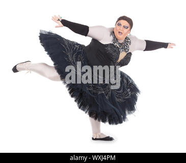 Overweight drag queen dancing in a tutu nimbly balancing on tiptoe with his foot raised in a fun caricature of a female ballet dancer, on white Stock Photo