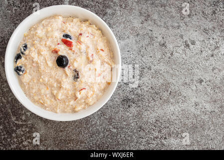 top view of cereal bowl filled with Bircher muesli with blueberries and cranberries on stone kitchen counter Stock Photo
