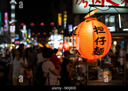 Kaohsiung, Taiwan: Orange chinese style lantern at night at Liuhe night market in Kaohsiung with blurry night market scene background Stock Photo