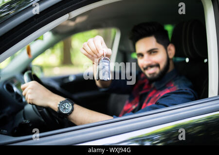 Happy hispanic man showing the key of his new car Stock Photo