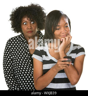 Overprotective mother with teenage daughter reading text messages Stock Photo