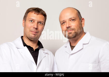 Two men in white coat smiling to the camera Stock Photo