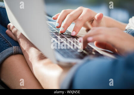 Typing hands of a schoolgirl and laptop close-up. Stock Photo