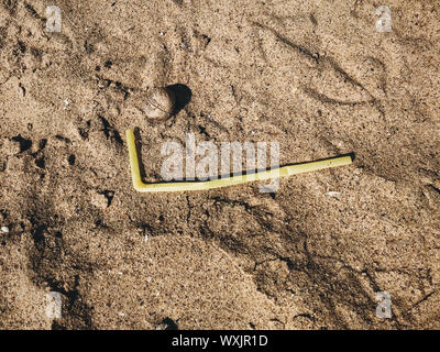 Single use plastic straw in sand, marine trash on the beach.Plastic pollution on the beach. Stop plastic pollution. Garbage at coast. Rubbish disaster Stock Photo