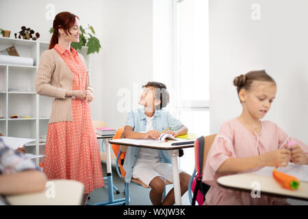 Red-haired teacher answering question of smart dark-haired boy Stock Photo