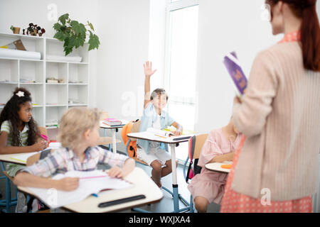 Dark-haired boy being very active during the English lesson Stock Photo