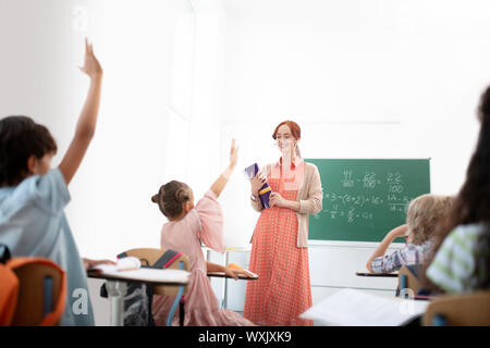 Red-haired teacher smiling while feeling satisfied with her pupils Stock Photo