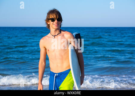Boy teen surfer happy holing surfboard on the beach shore Stock Photo ...