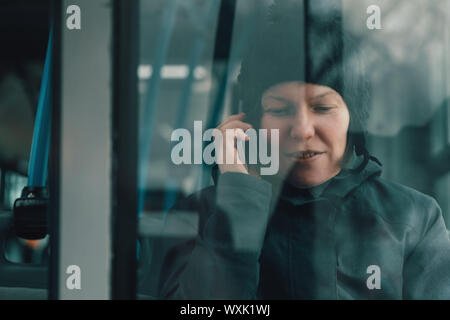 Beautiful adult woman talking on mobile phone in public bus in cold winter afternoon Stock Photo