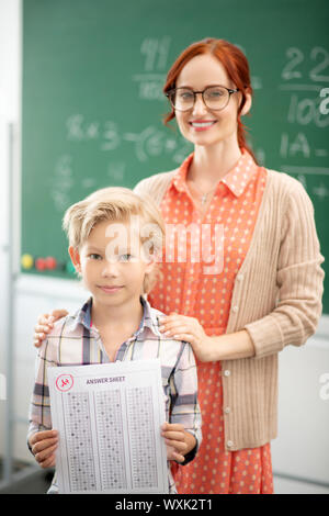 Teacher in glasses hugging her smart blonde pupil Stock Photo