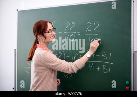 Smiling math teacher explaining new topic to her pupils Stock Photo