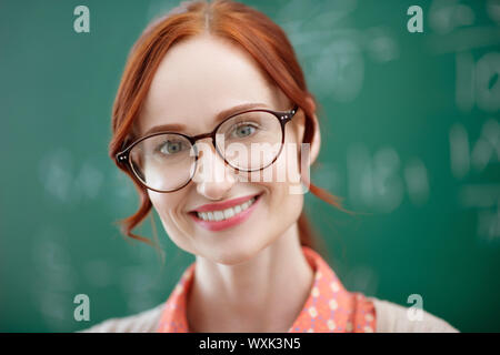 Teacher with natural makeup standing near blackboard Stock Photo