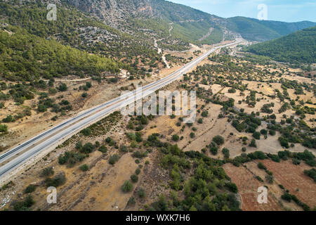 Asphalt road in the valley. Countryside highland landscape with agricultural fields and woods, aerial view.