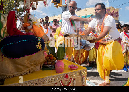 At the start of the Madrassi Parade for unity in the community, a devout Hindu man standing on one leg prays & does arti to the statue of Ganesh. Stock Photo