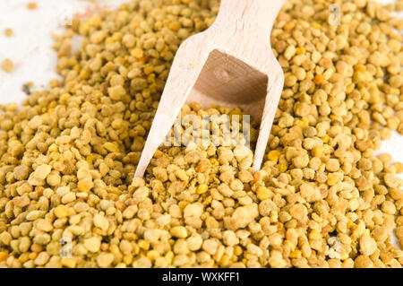 Bee pollen in wooden scoop. Nutritional supplement Stock Photo
