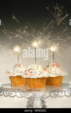 Cupcakes with sparklers on glass cake stand Stock Photo