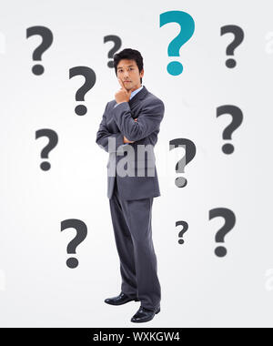 Questioning businessman on white background with question marks Stock Photo