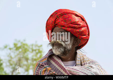 Man member of the Dhebariya Rabari community in traditional colorful cloth wearing a red turban, Great Rann of Kutch Desert, Gujarat, India Stock Photo