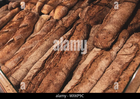 Dark bread baguettes on a bread shelf in a grocery store. Fresh bakery products. Rye bread. Stock Photo