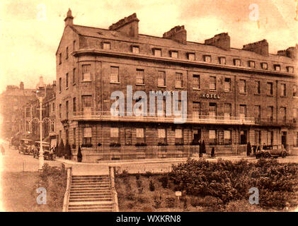 A Late Victorian or early 1900's picture of the former Kirby's Hotel, Whitby, Yorkshire England, with old motor vehicles and chauffeurs waiting outside. The building which once had an exclusive clientele is still in existence and stands next to the Royal Hotel on Whitby's West Cliff, overlooking the harbour. Stock Photo