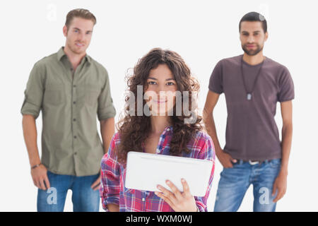 Stylish friends looking at camera with one holding tablet on white background Stock Photo