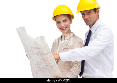 Two architects with construction plan and yellow helmets looking at the camera Stock Photo