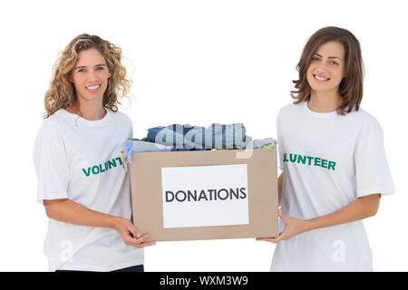 Two cheerful volunteers carrying clothes donation box on white background Stock Photo