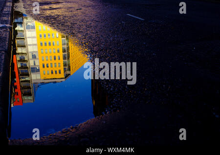 Colourful building of Central Saint Giles, reflected in a puddle. Central Saint Giles was designed by the Italian architect Renzo Piano. Denmark Stree Stock Photo