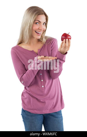 Young woman presenting an apple while looking at the camera Stock Photo